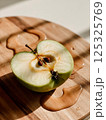 sliced green apple in drops of water on a white plate 125325769