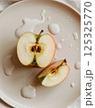 sliced green apple in drops of water on a white plate 125325770