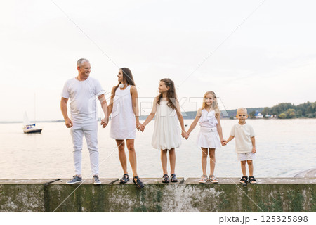Family of five is standing on pier by the water Family of five is standing on pier by the water 125325898