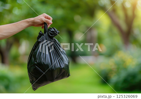 man hand hold black trash bag to go to throw in the bin.save ecology concept. Close up 125326069