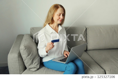 Woman holding plastic credit bank card, looking at laptop, shopping online or ordering goods at home Woman holding plastic credit bank card, looking at laptop, shopping online or ordering goods at home 125327106