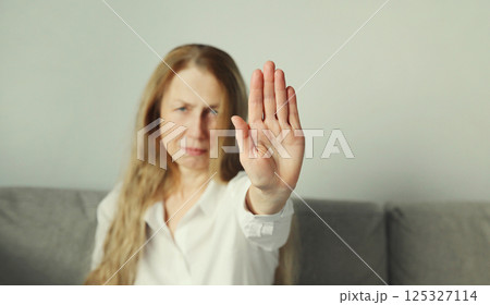 Woman shows stop, no or enough sign with palm of hand, refusal gesture, domestic violence 125327114