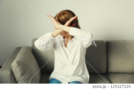 Woman shows stop, no or enough sign with palm of hand, refusal gesture, domestic violence 125327120