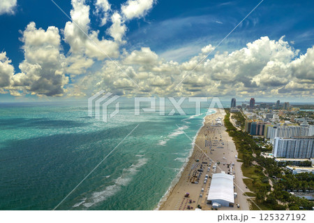 South Beach sandy surface with tourists relaxing on hot Florida sun. Tourism infrastructure in southern USA. Miami Beach city with high luxury hotels and condos 125327192