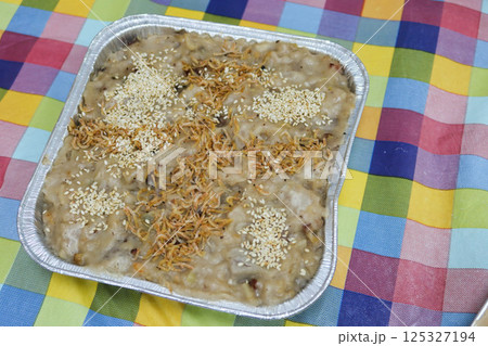close up of homemade Chinese New Year Yam pudding cake in aluminium foil tray with a colorful table cloth 125327194