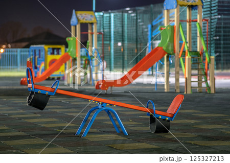 Seesaw swing in preschool yard with soft rubber flooring at night. 125327213