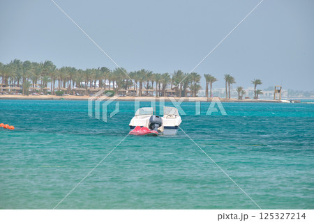 Seascape with ripple surface of blue sea water with white speedboat on anchor floating on calm waves 125327214