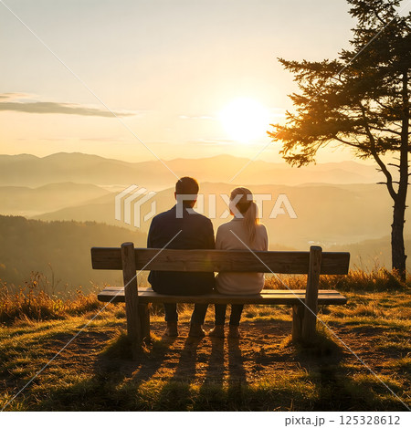 Sunset Serenity: A couple sits peacefully on a bench, silhouetted against a vibrant sunset. 125328612