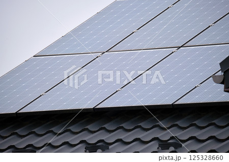 Residential house with rooftop covered with solar photovoltaic panels for producing of clean ecological electrical energy in suburban rural area. Concept of autonomous home Residential house with rooftop covered with solar photovoltaic panels for producing of clean ecological electrical energy in suburban rural area. Concept of autonomous home 125328660