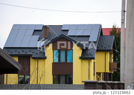 Residential house with rooftop covered with solar photovoltaic panels for producing of clean ecological electrical energy in suburban rural area. Concept of autonomous home Residential house with rooftop covered with solar photovoltaic panels for producing of clean ecological electrical energy in suburban rural area. Concept of autonomous home 125328662