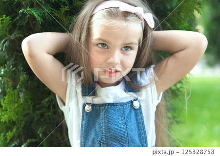 Portrait of pretty child girl standing outdoors in summer park smiling happily. 125328758