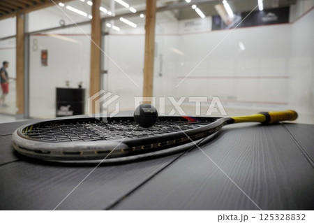 squash racket with ball close up, laying on table, preparing for game. court background, live pictures squash racket with ball close up, laying on table, preparing for game. court background, live pictures 125328832