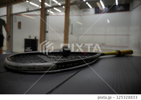 squash racket with ball close up, laying on table, preparing for game. court background, live pictures squash racket with ball close up, laying on table, preparing for game. court background, live pictures 125328833