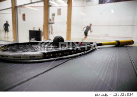 squash racket with ball close up, laying on table, preparing for game. court background, live pictures 125328834