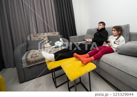Gaming siblings enjoy an exciting evening in a cozy living room filled with fun, laughter, and moments of friendly competition while playing video games together 125329044