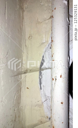 Cobwebs around a pipe in a dimly lit corner of a room 125329131