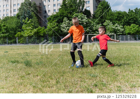 Two boys playing soccer on sunny green field. Two boys playing soccer on sunny green field. 125329228