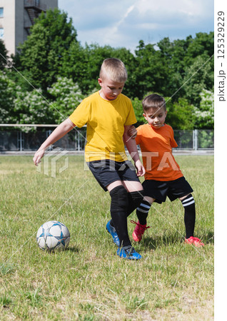 Two boys competing for soccer ball on green field. Two boys competing for soccer ball on green field. 125329229