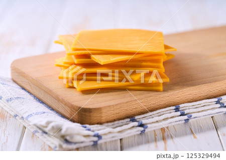 cheddar cheese slices on a wooden table, close up. 125329494