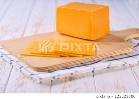 Slices of cheddar cheese on a cutting board, selective focus. 125329500