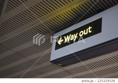 Illuminated Way Out Sign with Arrow in Modern Indoor Public Transportation Area 125329526