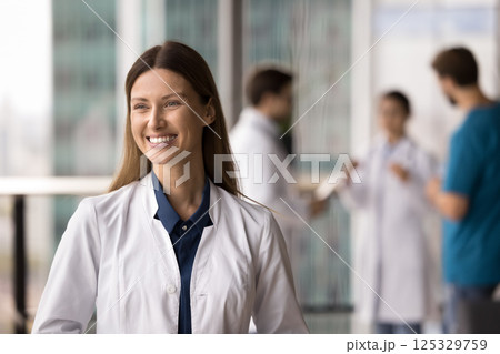 Cheerful smiling millennial woman doctor excited with professional success Cheerful smiling millennial woman doctor excited with professional success 125329759