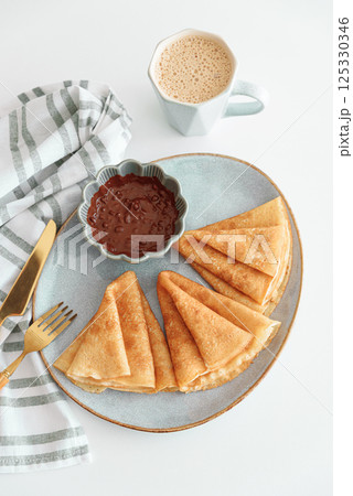 Crepes with chocolate cream and coffee on white wooden table. Pancake day, Maslenitsa. Top view 125330346