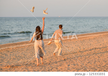 Girl throws sandals up in the ocean. Beginning of vacation, honeymoon Girl throws sandals up in the ocean. Beginning of vacation, honeymoon 125331031