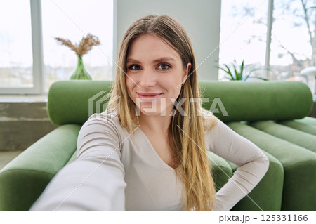 Selfie portrait happy beautiful young woman in home interior 125331166