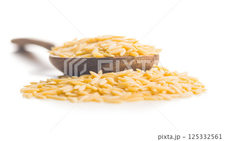 Orzo, kritharaki, risoni pasta. Uncooked dry pasta in spoon isolated on white background. Orzo, kritharaki, risoni pasta. Uncooked dry pasta in spoon isolated on white background. 125332561