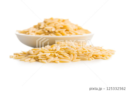 Orzo, kritharaki, risoni pasta. Uncooked dry pasta in bowl isolated on white background. 125332562