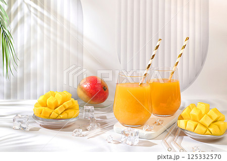 Homemade cocktail, juice or lemonade with mango slices and ice on a sunny kitchen table. Refreshing summer diet drink recipe, Detox diet and summer party concept. Restaurant menu, selective approach 125332570