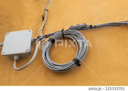 Coiled Electric Cable on Yellow Wall 125332701