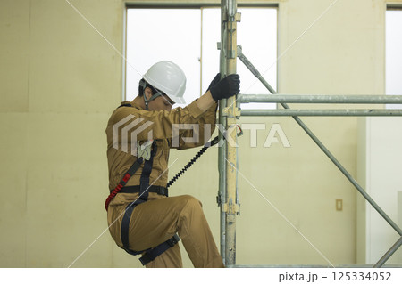 フルハーネスを装着し足場を登る作業員の男性　 125334052