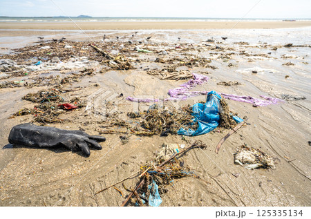 Human waste covers a tropical beach with plastic bags and debris scattered along the coastline. Global crisis of marine pollution and environmental contamination. Beach pollution crisis. Ocean waste. 125335134