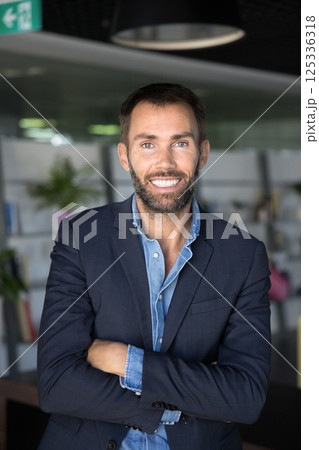 Handsome middle-aged businessman in formal jacket posing in workspace Handsome middle-aged businessman in formal jacket posing in workspace 125336318