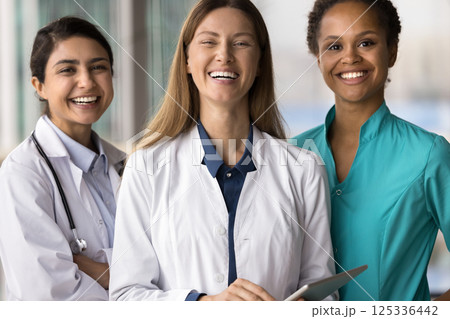 Group portrait three happy smiling young women doctors different ethnicities 125336442