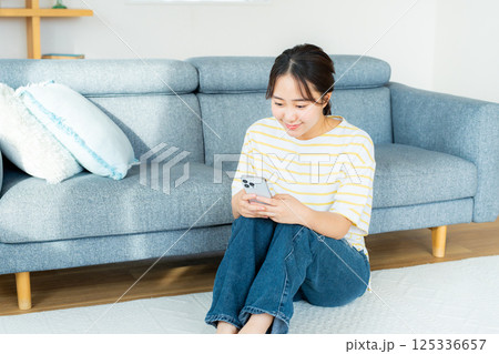 部屋でスマホを操作する若い女性 部屋でスマホを操作する若い女性 125336657