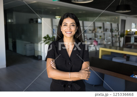 Attractive businesswoman posing in office with her arms-crossed Attractive businesswoman posing in office with her arms-crossed 125336668