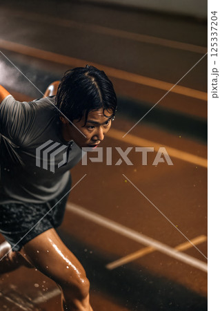 Athlete Sprinting on a Track in a Training Session During Indoor Practice at Night 125337204