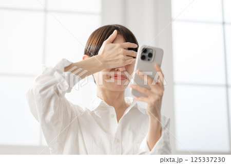 スマートフォンを見て驚く女性 125337230
