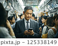 混んでいる電車に乗りスマホを見るビジネスマン 125338149