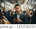 混んでいる電車に乗りスマホを見るビジネスマン 125338150