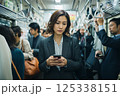 混んでいる電車に乗りスマホを見ている若い女性 125338151