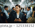 混んでいる電車に乗りスマホを見ている若い女性 125338152
