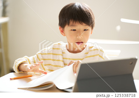 タブレットを見ながらオンライン学習をする男子小学生 125338718