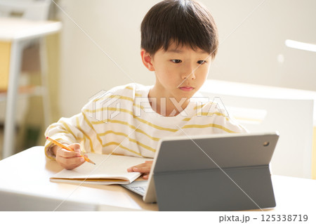 タブレットを見ながらオンライン学習をする男子小学生 125338719