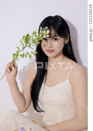 Portrait of a young woman sitting and holding flowers 125339228