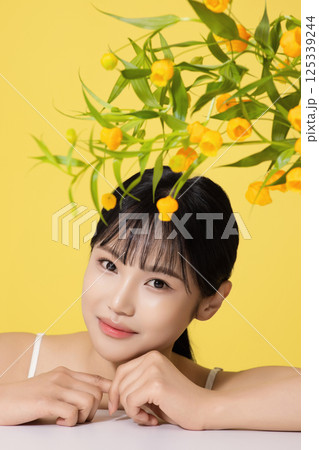Portrait of a young woman lying face down in front of a table with a vase on it 125339244