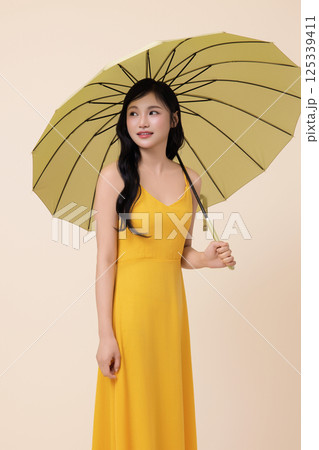A woman in her 20s wearing a yellow umbrella 125339411